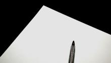 Image of black piece of paper with a pen on top of it